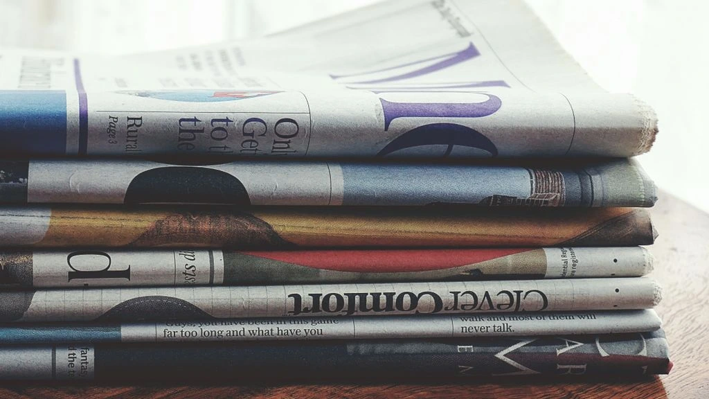 A morning newspaper and coffee on a kitchen table at dawn